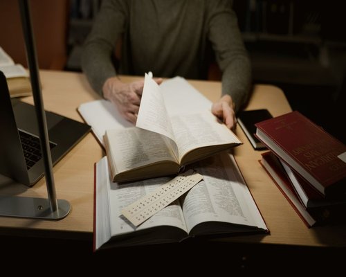 An open physical hardcover book illuminated by a soft yellow task light on a table in a cozy corner setup