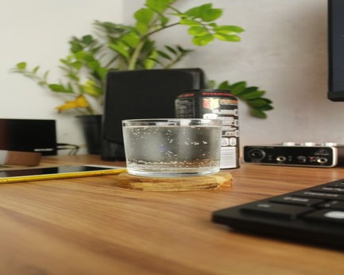 A clean glass of fresh mineral water standing on a contemporary workspace desktop setup